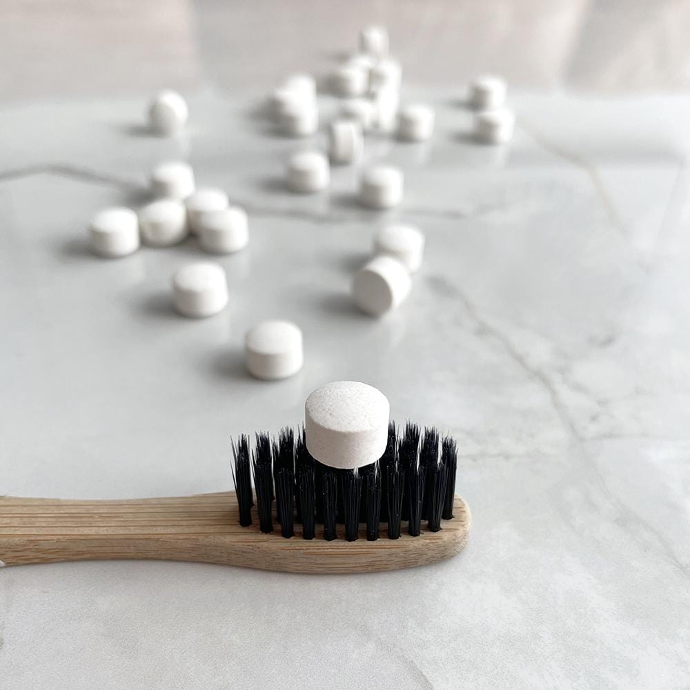 Toothbrush showing one tab on its bristles with some scattered tabs around it